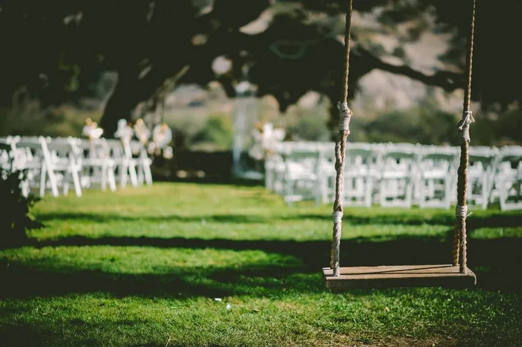 Sillas blancas para la ceremonia en el césped, bajo los árboles