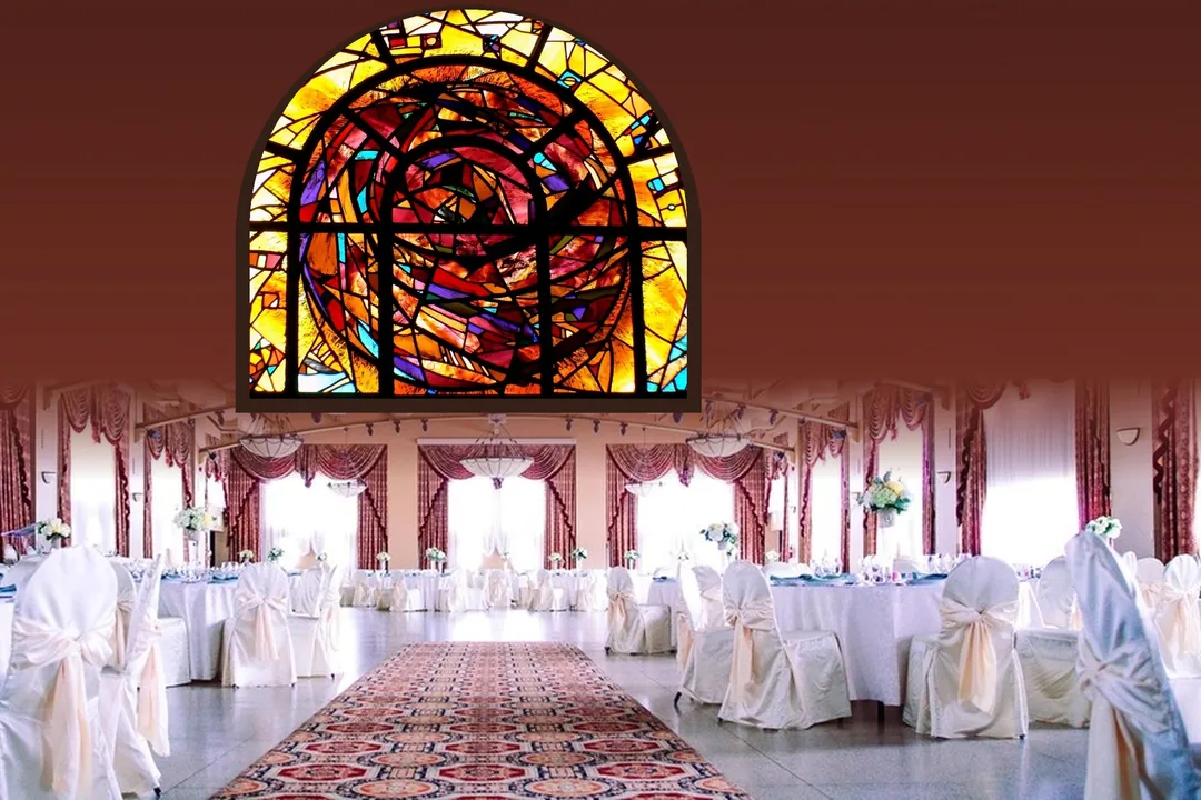 Un salón de banquetes con una alfombra hasta el fondo y, arriba, una gran vidriera de colores